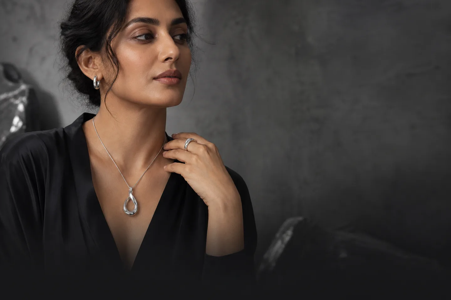 Model wearing an EMIRA sterling silver teardrop pendant, hoop earrings and ring